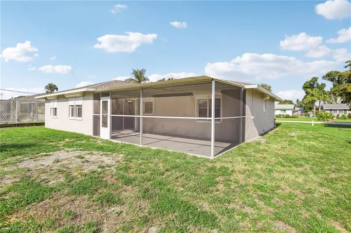 Rear view of house featuring a sunroom and a lawn