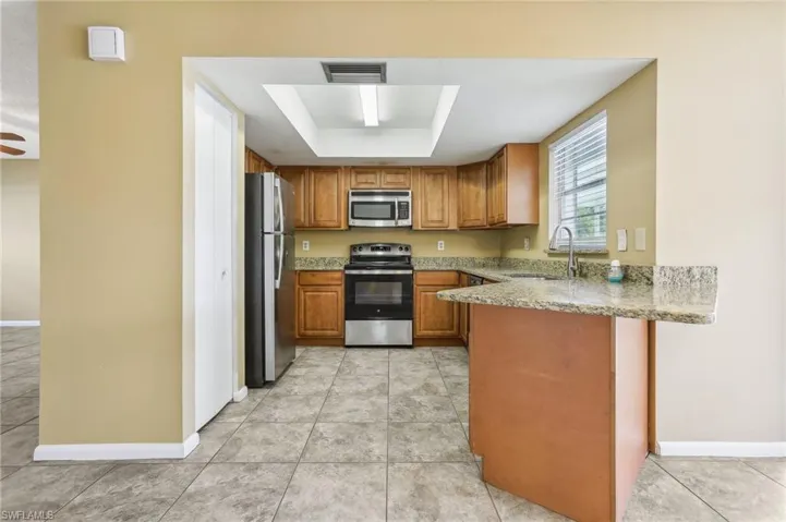 Kitchen featuring appliances with stainless steel finishes, sink, and light tile floors