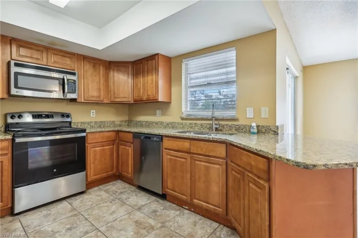 Kitchen with sink, light tile flooring, kitchen peninsula, and stainless steel appliances