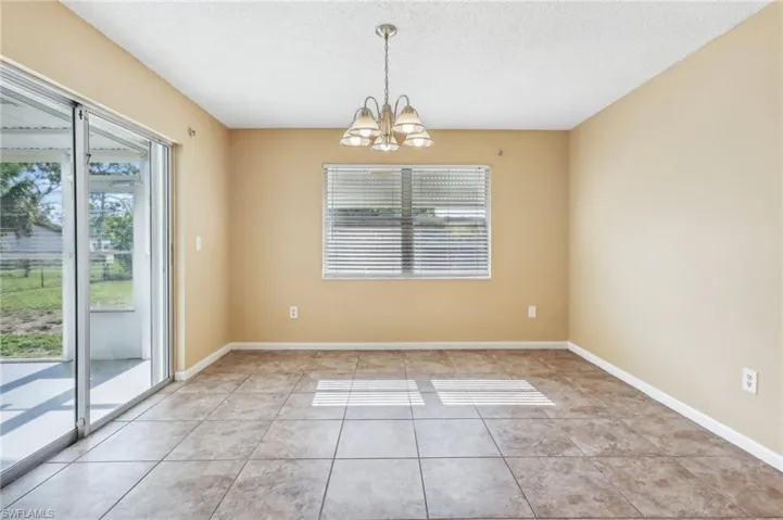 Unfurnished room featuring an inviting chandelier, a textured ceiling, and light tile floors
