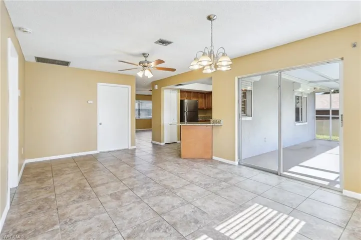 Tiled spare room featuring ceiling fan with notable chandelier
