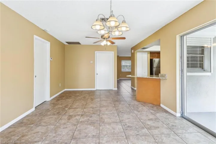 Spare room featuring light tile floors and ceiling fan with notable chandelier
