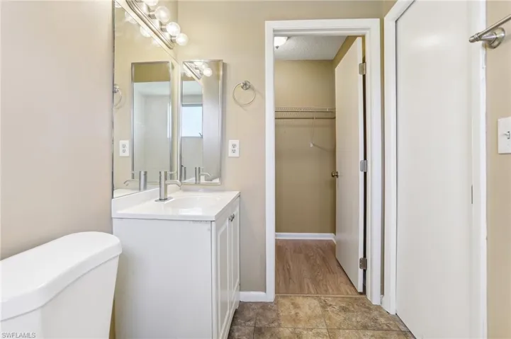Bathroom with wood-type flooring, vanity with extensive cabinet space, toilet, and a textured ceiling