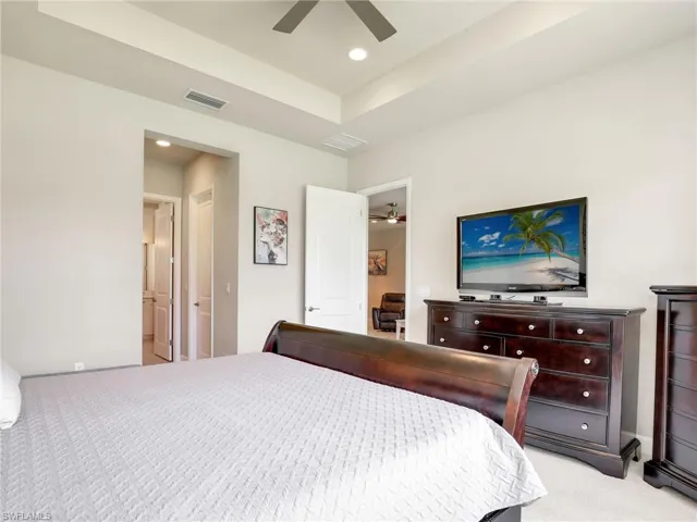 Carpeted bedroom featuring a tray ceiling and ceiling fan