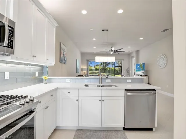 Kitchen with appliances with stainless steel finishes, ceiling fan, light tile floors, and pendant lighting