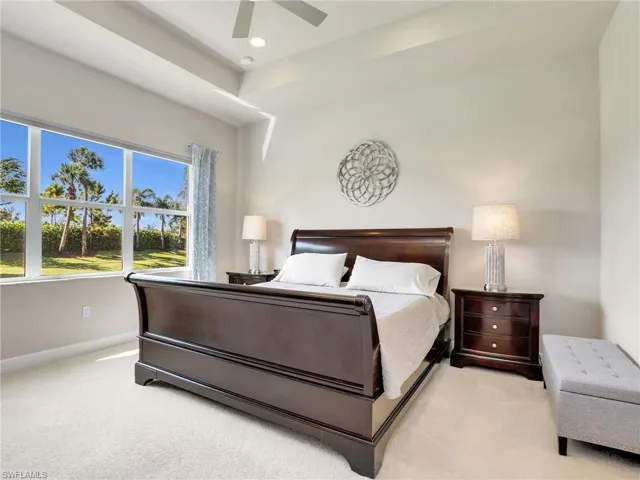 Bedroom with a raised ceiling, ceiling fan, and carpet flooring
