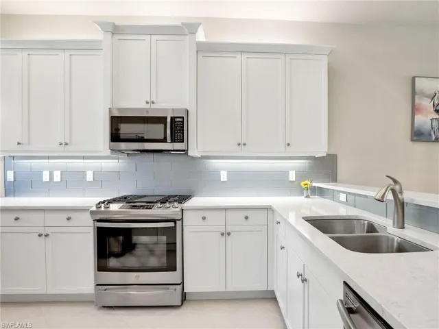Kitchen featuring sink, tasteful backsplash, light tile flooring, and stainless steel appliances
