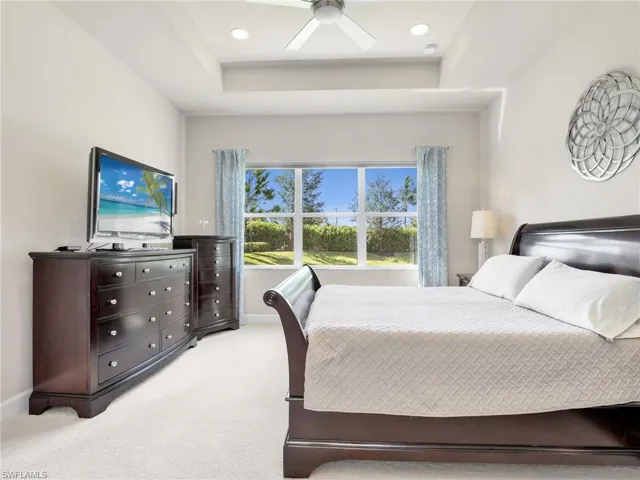 Bedroom featuring carpet flooring, ceiling fan, and a raised ceiling