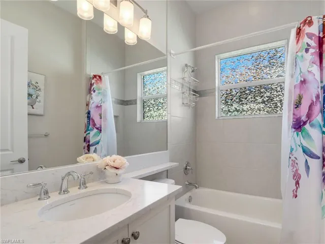 Full bathroom with oversized vanity, toilet, and shower / bath combination with curtain