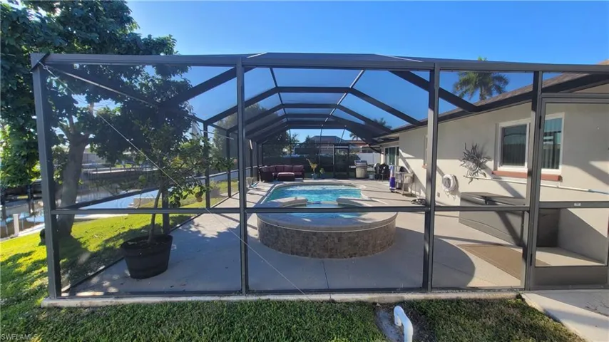 View of patio featuring glass enclosure, a sunroom, and a jacuzzi