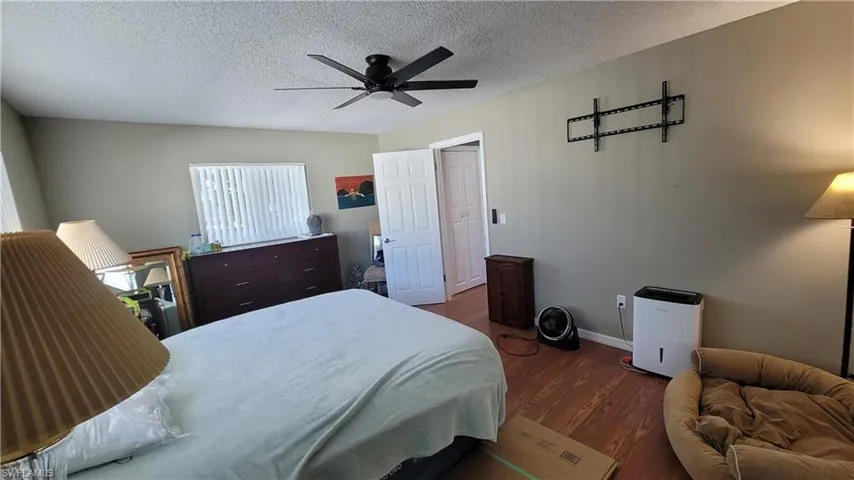Bedroom featuring dark wood-type flooring, a ceiling fan, and a textured ceiling