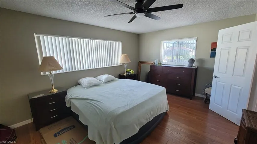 Bedroom with dark wood-style floors, a ceiling fan, and a textured ceiling
