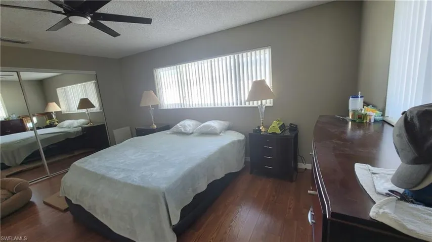 Bedroom with dark wood-type flooring, ceiling fan, a textured ceiling, and a closet