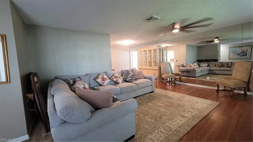 Living area featuring a textured ceiling, wood finished floors, and a ceiling fan