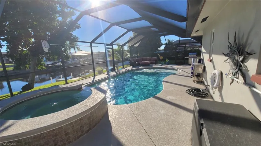 View of swimming pool with a sunroom, a lanai, a pool with connected hot tub, a patio area, and a grill