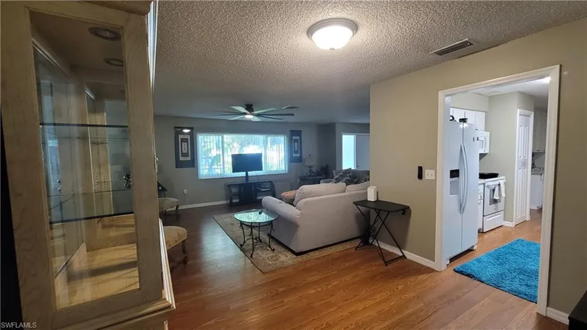 Living room with light wood-type flooring, a textured ceiling, and a ceiling fan