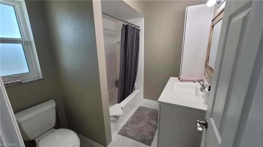 Full bath featuring vanity, shower / bath combo, and a textured wall