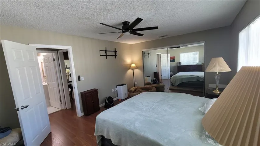 Bedroom featuring a closet, a textured ceiling, dark wood-style flooring, and ceiling fan