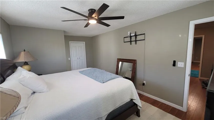 Bedroom featuring wood finished floors, a closet, a textured ceiling, and ceiling fan