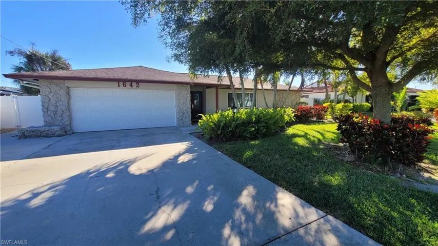 Single story home with concrete driveway, a garage, a front lawn, stone siding, and stucco siding