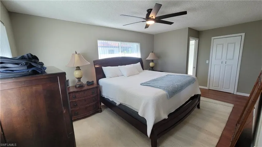 Bedroom with wood finished floors, ceiling fan, a textured ceiling, and a closet