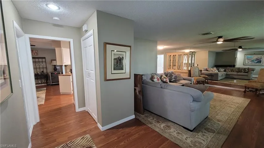 Living area featuring a textured ceiling, wood finished floors, a ceiling fan, and beverage cooler