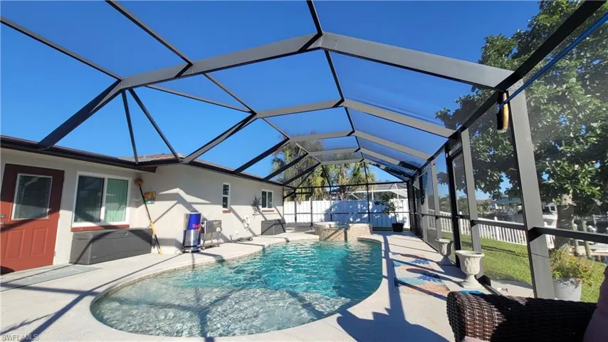 View of pool with glass enclosure, a sunroom, and a patio area