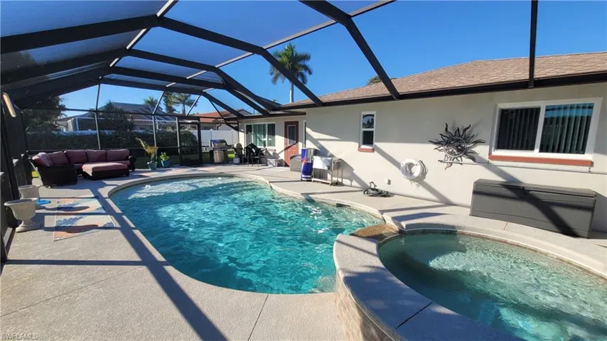 View of swimming pool featuring a patio, a sunroom, glass enclosure, a pool with connected hot tub, and an outdoor living space