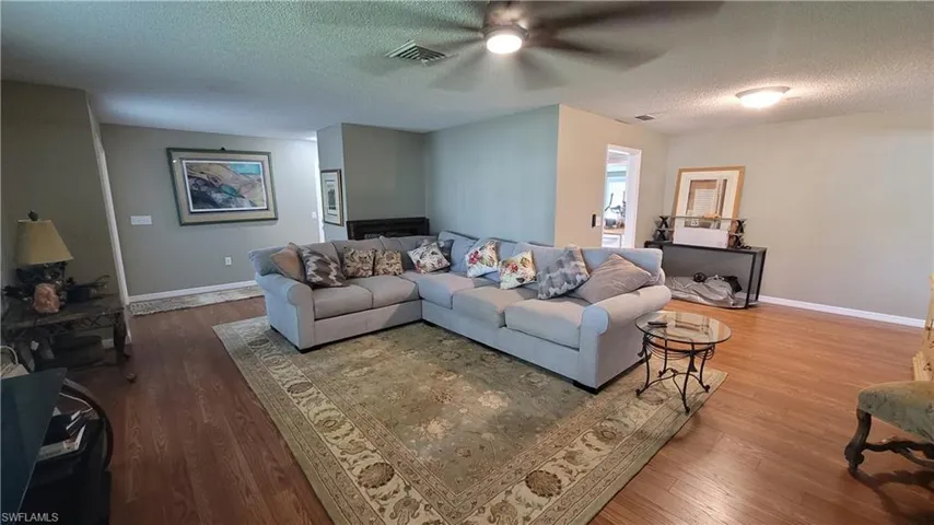 Living room with a textured ceiling, wood finished floors, and ceiling fan
