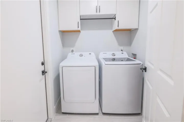 Washroom featuring independent washer and dryer and cabinets