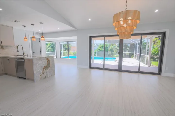 Unfurnished living room with sink, vaulted ceiling, and light tile patterned flooring