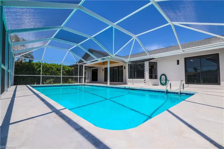 View of swimming pool with glass enclosure and a patio area