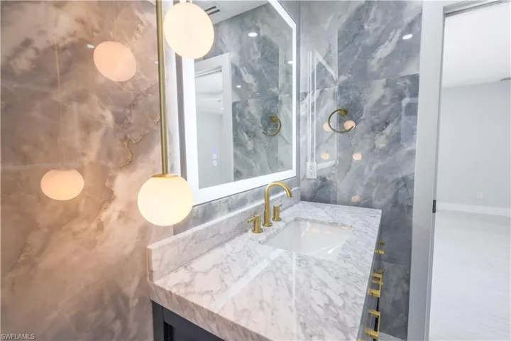 Bathroom with tile walls, decorative backsplash, and vanity