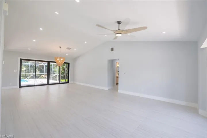 Spare room featuring vaulted ceiling, ceiling fan with notable chandelier, and light tile patterned floors