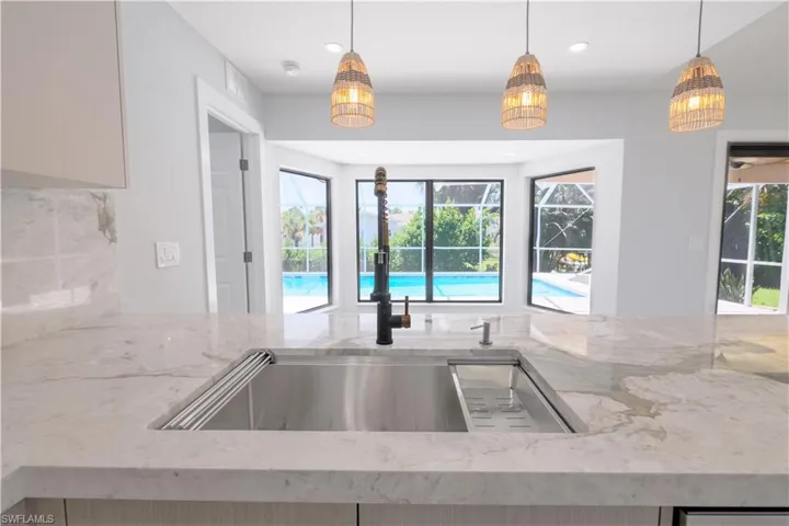 Kitchen with hanging light fixtures and light stone countertops