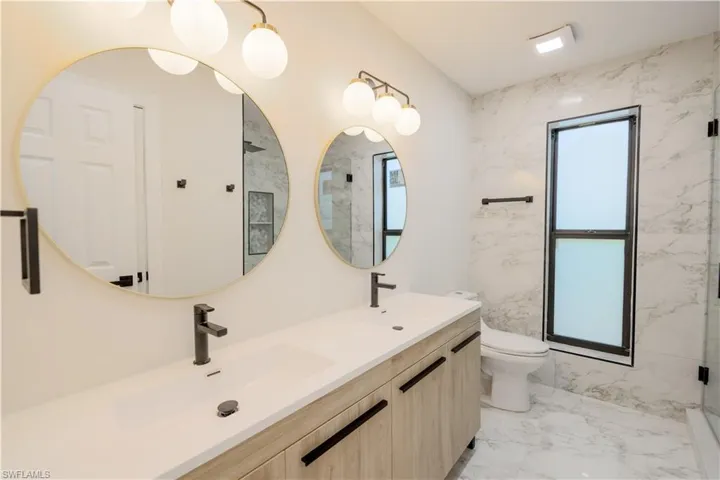 Bathroom featuring walk in shower, toilet, dual bowl vanity, and tile patterned floors