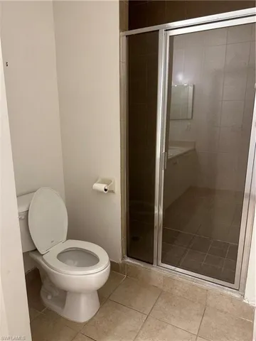 Bathroom with toilet, tile patterned floors, and a shower with door