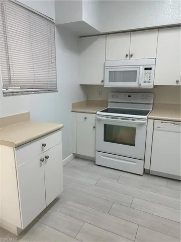 Kitchen featuring white cabinetry, white range oven, and dishwasher