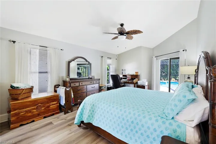 Bedroom with wood finished floors, access to outside, lofted ceiling, and ceiling fan