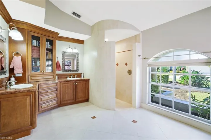Bathroom featuring double vanity, a walk in shower, light tile patterned flooring, and tile walls