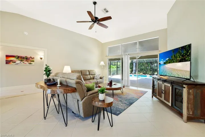 Living area with light tile patterned floors, ceiling fan, and high vaulted ceiling