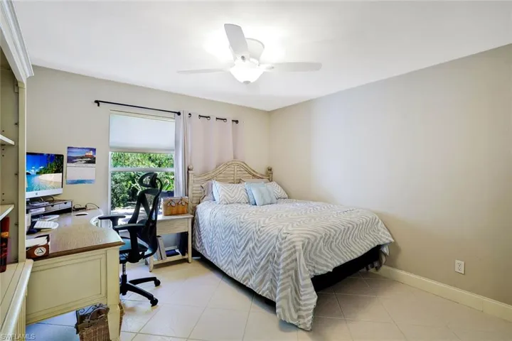 Bedroom featuring an office area, light tile patterned flooring, and a ceiling fan