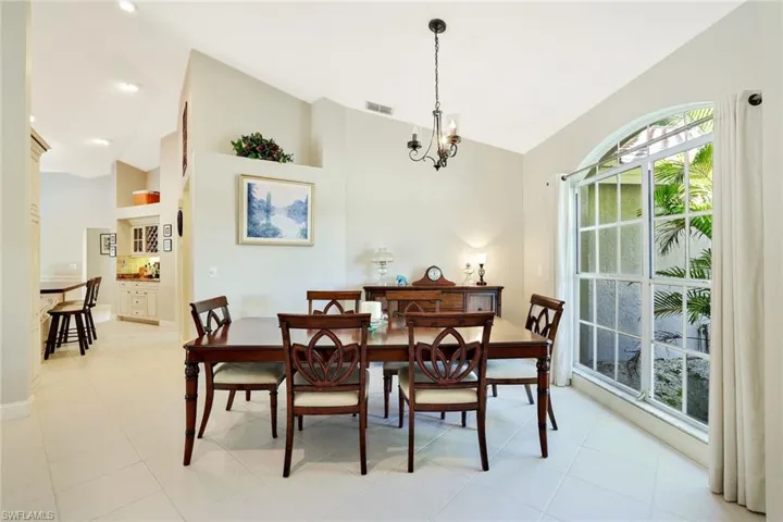 Dining space with high vaulted ceiling, light tile patterned flooring, and a chandelier