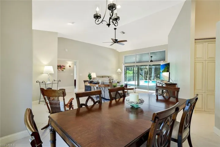 Dining space with a chandelier, light tile patterned floors, a ceiling fan, and vaulted ceiling
