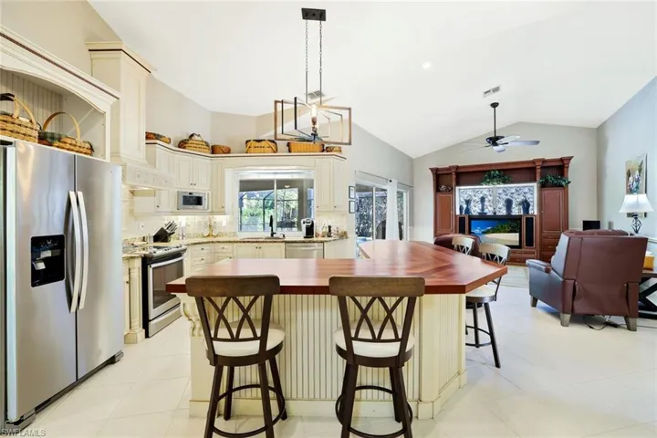 Kitchen with appliances with stainless steel finishes, decorative backsplash, butcher block counters, a breakfast bar area, and a kitchen island