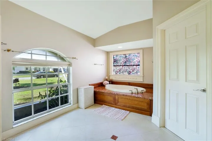 Bathroom with a bath, lofted ceiling, and light tile patterned floors