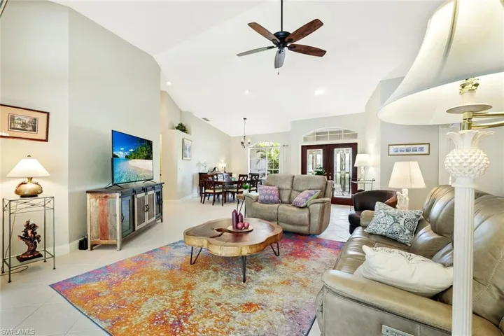 Living room with high vaulted ceiling, ceiling fan, light tile patterned floors, french doors, and recessed lighting