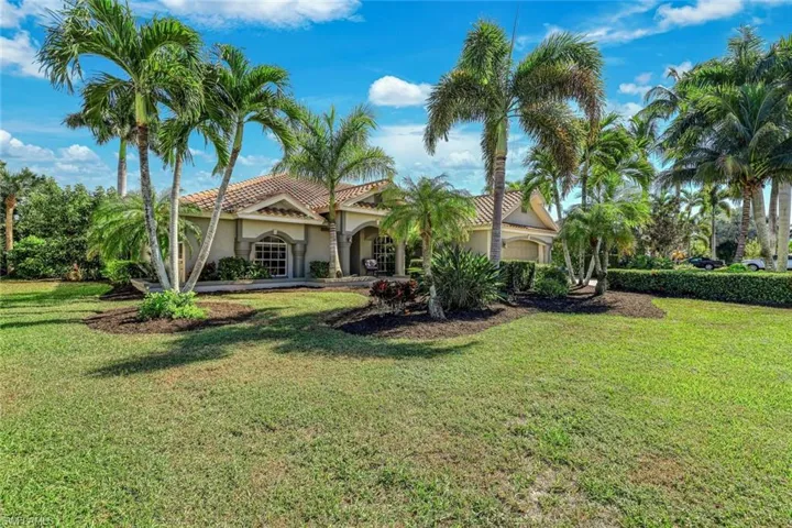 View of front of property with stucco siding, a front yard, and a tile roof