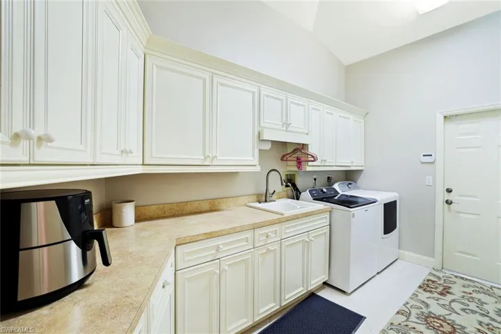 Washroom with light tile patterned floors, washer and clothes dryer, and cabinet space