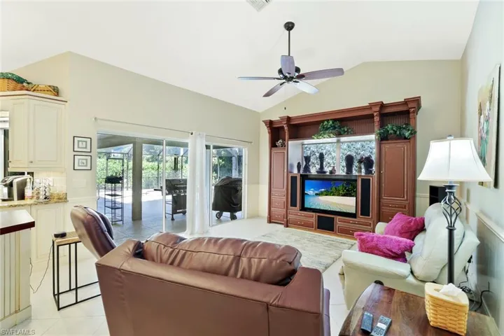 Living area with vaulted ceiling, a ceiling fan, and light tile patterned floors